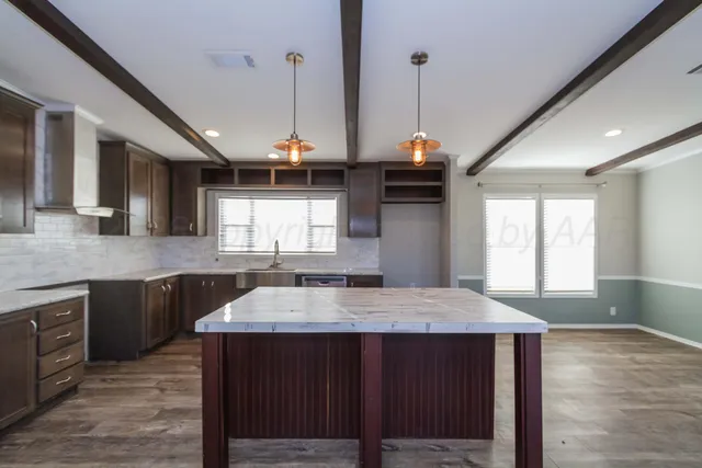 a kitchen with kitchen island granite countertop a stove a sink a refrigerator dining table and chairs