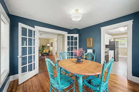 a dining room with furniture a rug a potted plant and wooden floor