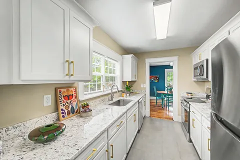 a large kitchen with stainless steel appliances granite countertop a lot of counter space and wooden floors
