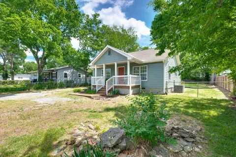 a view of a house with a backyard and a tree