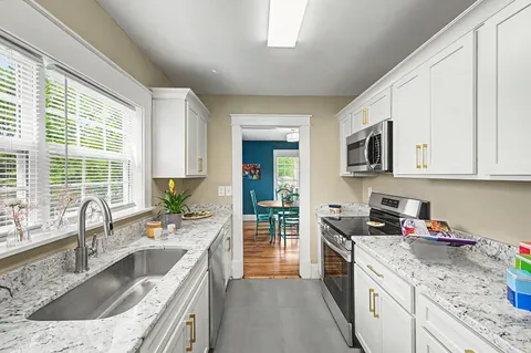 a kitchen with granite countertop a sink a counter top space appliances and cabinets