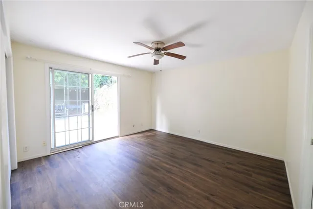 an empty room with wooden floor ceiling fan and windows