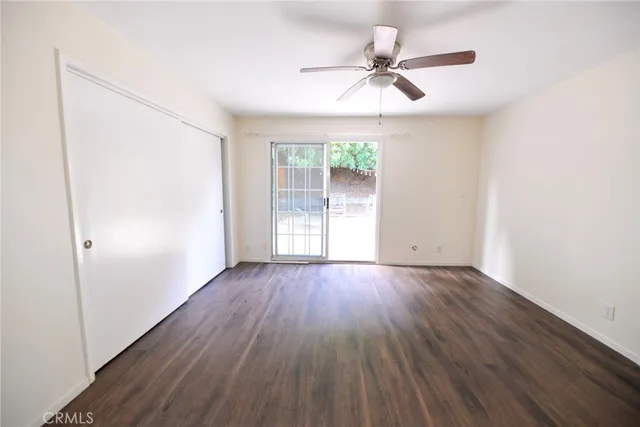 an empty room with wooden floor fan and windows