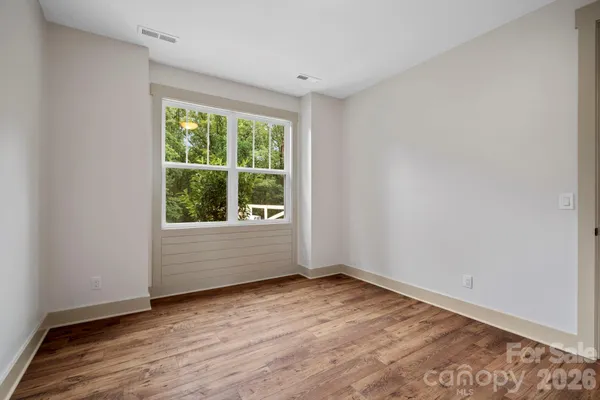 a view of an empty room with window and wooden floor
