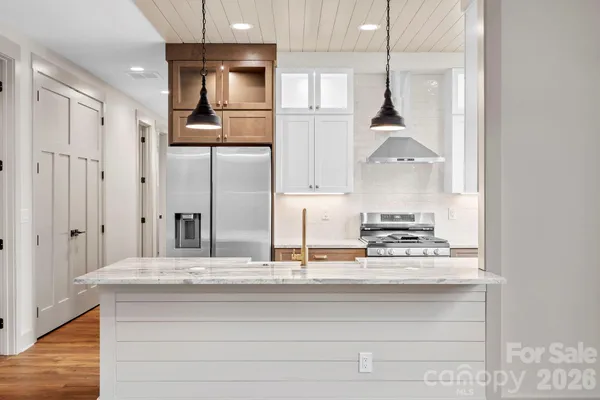 a kitchen with stainless steel appliances granite countertop a refrigerator a stove and a sink with wooden floor