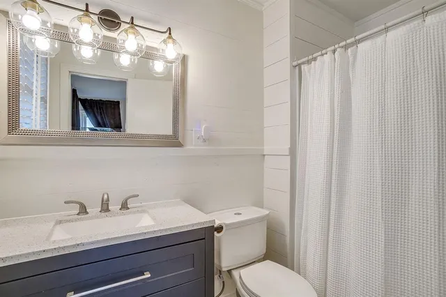 a bathroom with a granite countertop sink vanity mirror and toilet