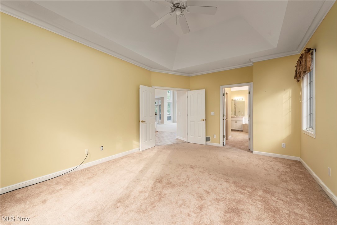 455 Old Reservoir Road Berea, OH 44017 - Photo 15 of 49 Unfurnished bedroom featuring light carpet, ensuite bath, ceiling fan, ornamental molding, and a tray ceiling