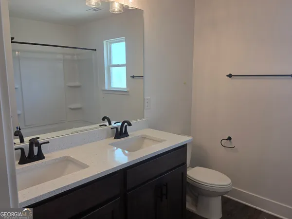 a bathroom with a sink a toilet a mirror and shower