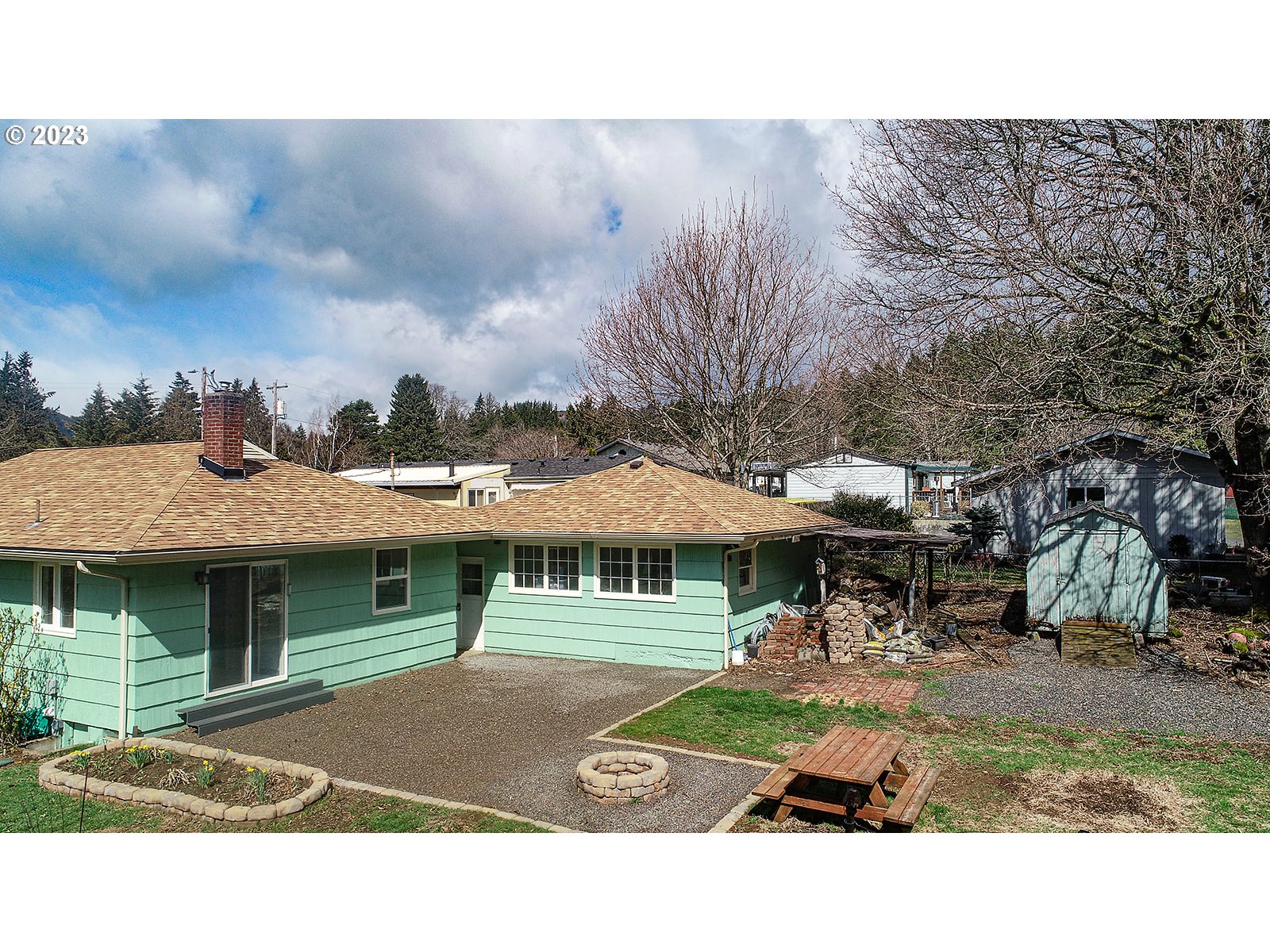 390 Northwest Chesser Road Stevenson, WA 98648 - Photo 32 of 42 a view of a patio with table and chairs under an umbrella with large trees