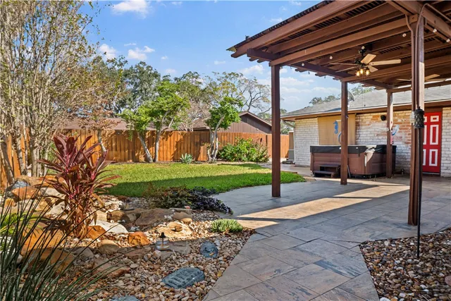a view of a backyard with brick wall and potted plants