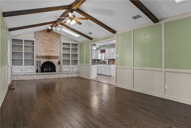 an empty room with wooden floor a fireplace and windows