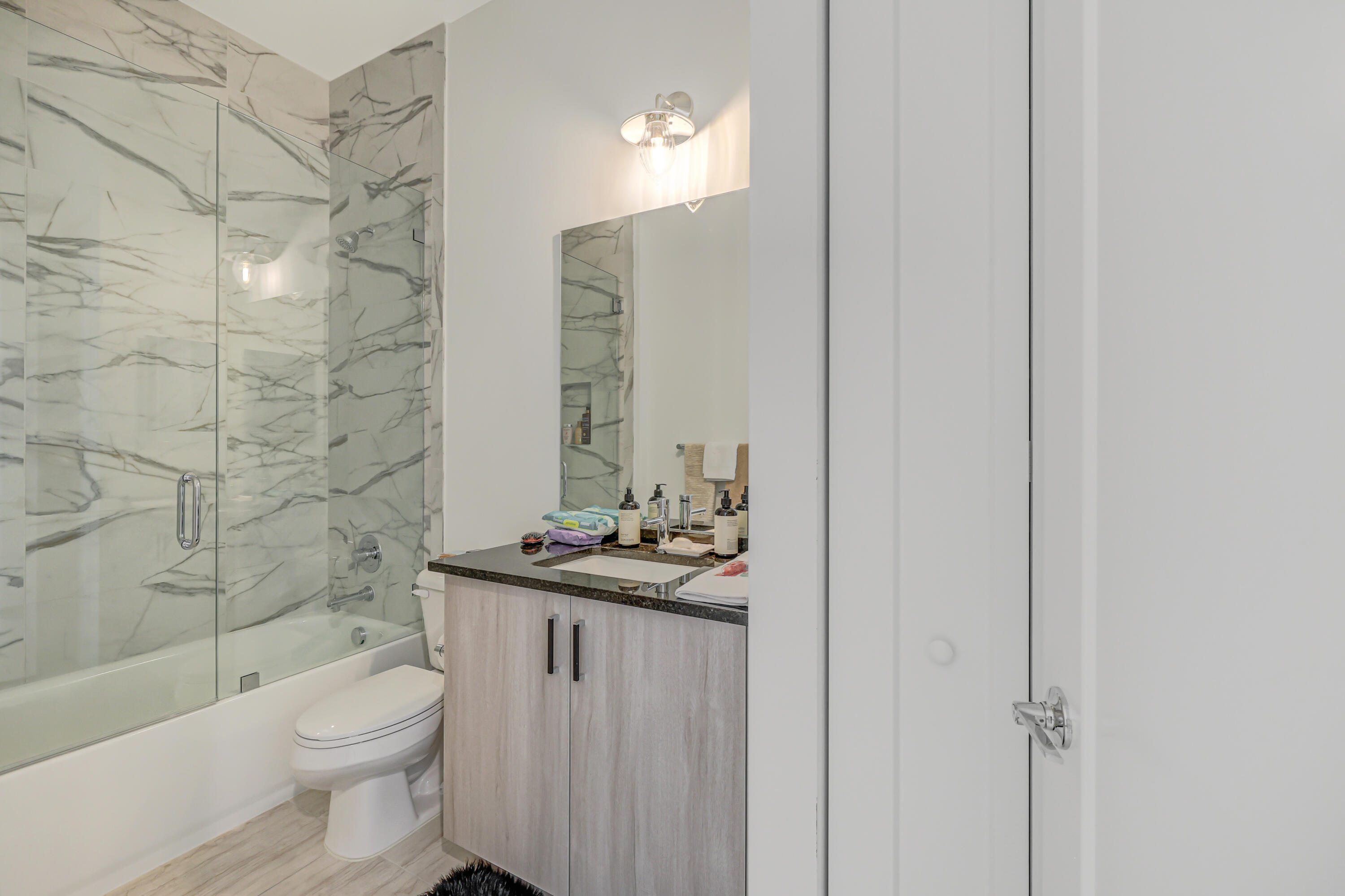 8283 Royal County Down Road Boca Raton, FL 33434 - Photo 26 of 88 a bathroom with a granite countertop toilet a sink a mirror and shower