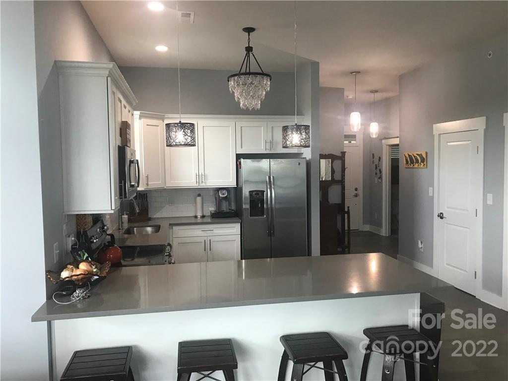 935 McAlway Road, Unit 306 Charlotte, NC 28211 - Photo 15 of 35 a kitchen with kitchen island a counter top space a sink stainless steel appliances and cabinets
