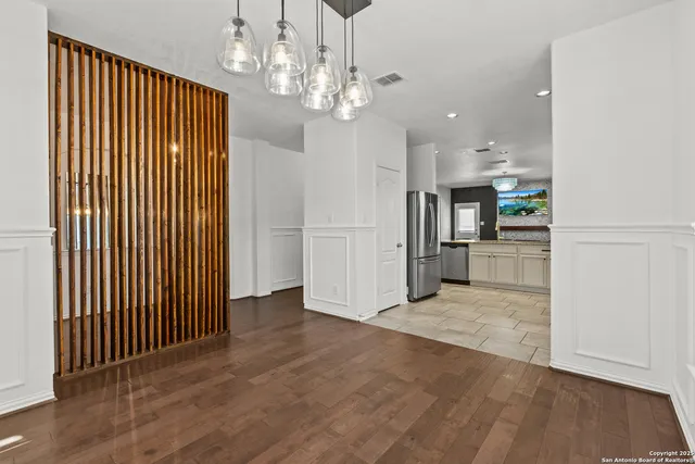 an empty room with kitchen view and wooden floor