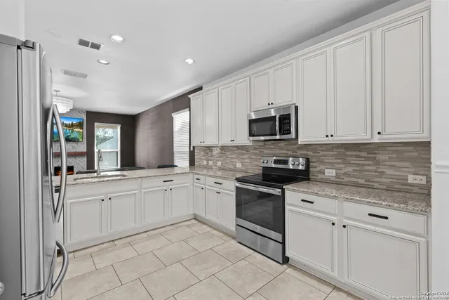 a kitchen with white cabinets and appliances