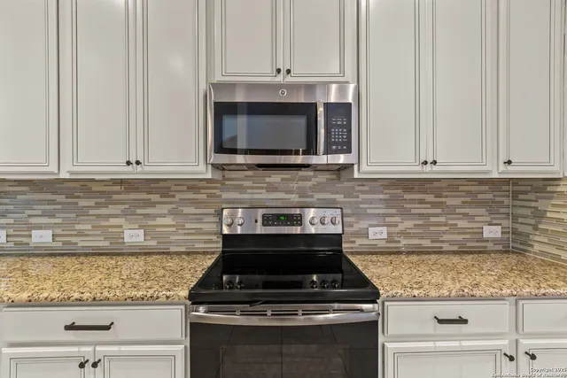 a kitchen with granite countertop white cabinets and stainless steel appliances