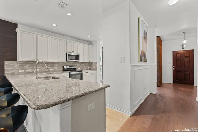 a kitchen with stainless steel appliances granite countertop a sink refrigerator and cabinets