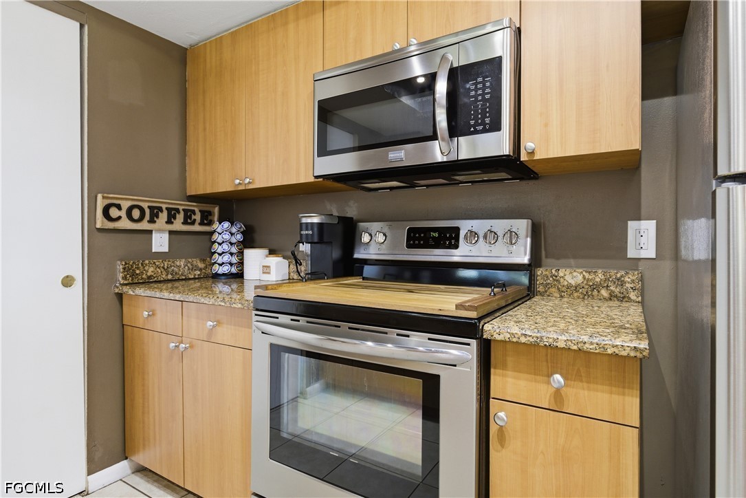 4960 20th Place Southwest Naples, FL 34116 - Photo 13 of 33 a kitchen with granite countertop a stove top oven microwave and cabinets