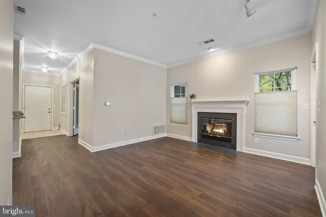 a view of an empty room with wooden floor fireplace and a window