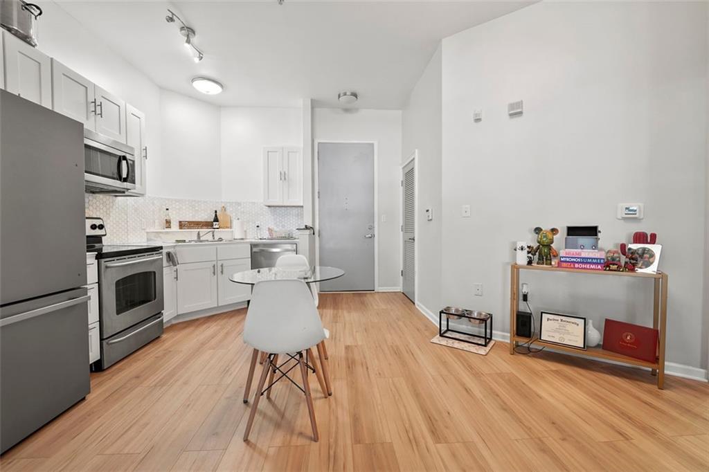 898 Oak Street Southwest, Unit 1105 Atlanta, GA 30310 - Photo 11 of 20 a kitchen with stainless steel appliances a stove top oven a sink dishwasher and a refrigerator with wooden floor