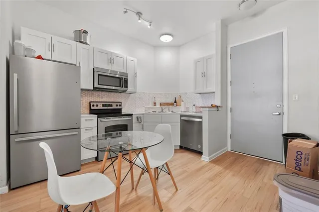 a kitchen with stainless steel appliances a refrigerator stove a sink and chairs