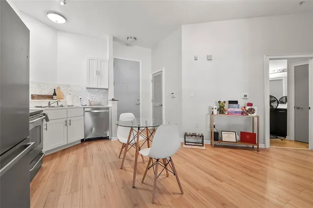 a kitchen with stainless steel appliances a stove top oven a sink dishwasher and a refrigerator with wooden floor