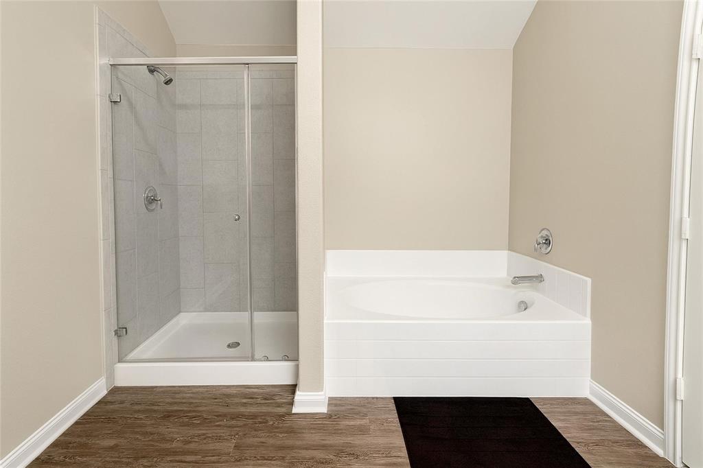 1837 Rialto Lane Crowley, TX 76036 - Photo 19 of 24 Bathroom featuring a glass-enclosed shower with tile surround, a built-in soaking tub, wood-finish flooring, and light neutral wall paint