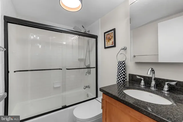a bathroom with a granite countertop sink toilet and a mirror