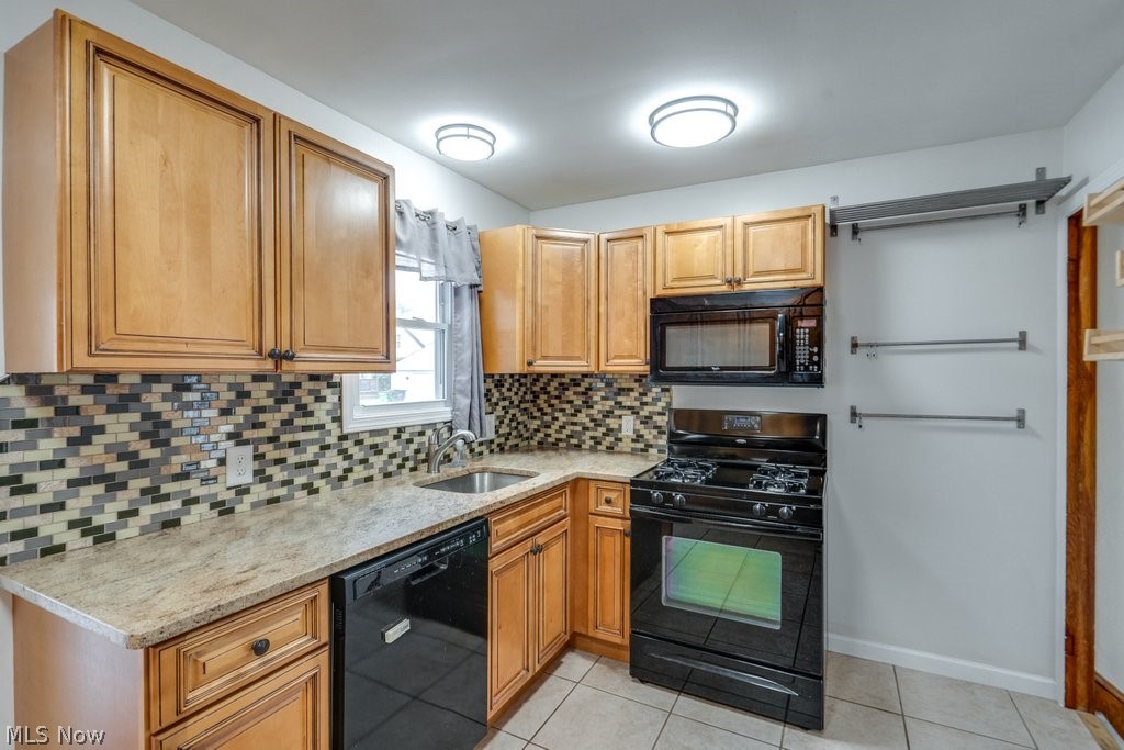 30000 Elgin Road Wickliffe, OH 44092 - Photo 3 of 30 Kitchen featuring wood cabinetry, granite-style countertops, a mosaic tile backsplash, black appliances, and neutral tile flooring