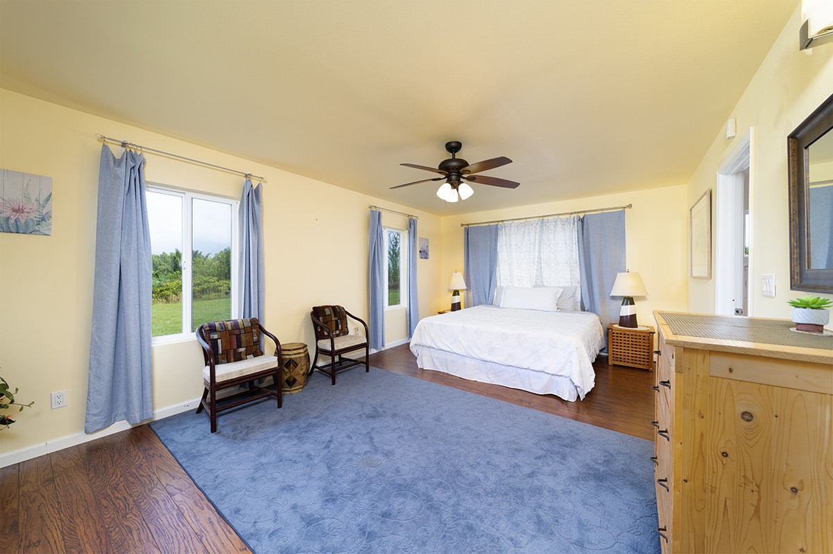 28-380 Sugar Mill Road Pepeekeo, HI 96783 - Photo 13 of 29 a spacious bedroom with a bed and wooden floor