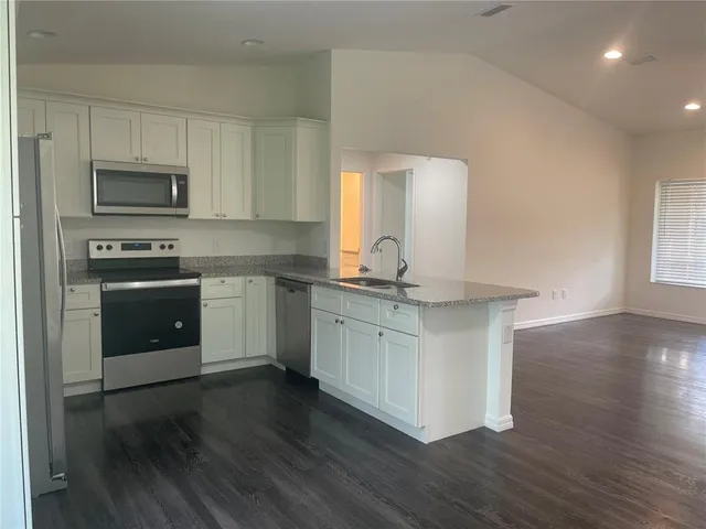 a kitchen with stainless steel appliances granite countertop a stove a sink and a microwave