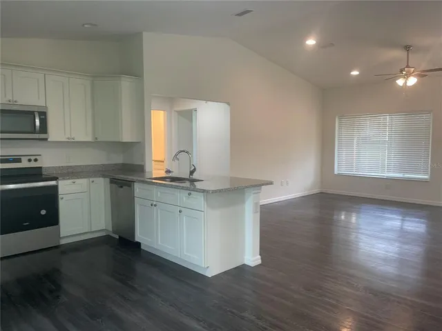 a kitchen with wooden floors and white cabinets