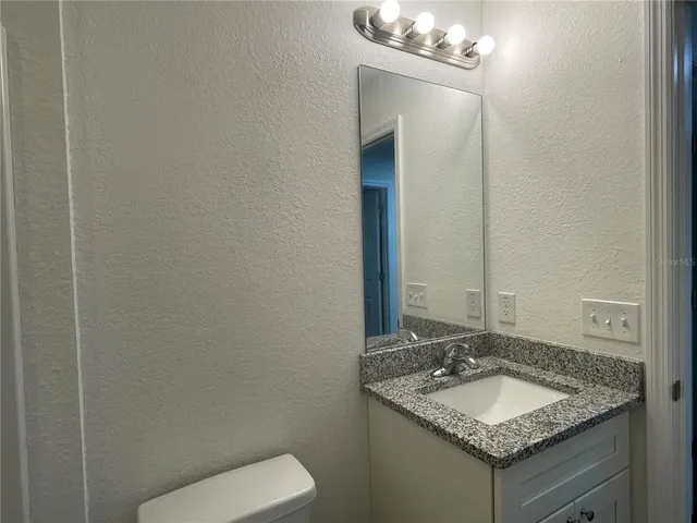 a bathroom with a granite countertop sink and a mirror