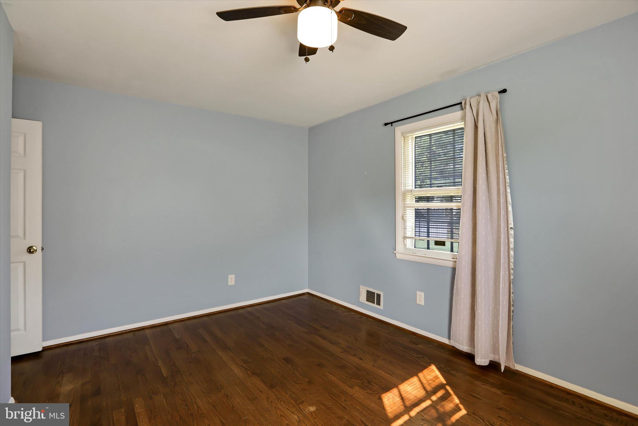 8314 Tinsley Road Baltimore, MD 21244 - Photo 14 of 44 an empty room with wooden floor chandelier fan and windows