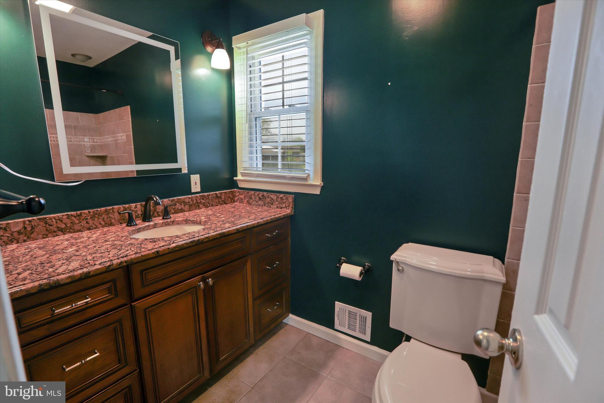 8314 Tinsley Road Baltimore, MD 21244 - Photo 17 of 44 a bathroom with a granite countertop toilet sink and mirror