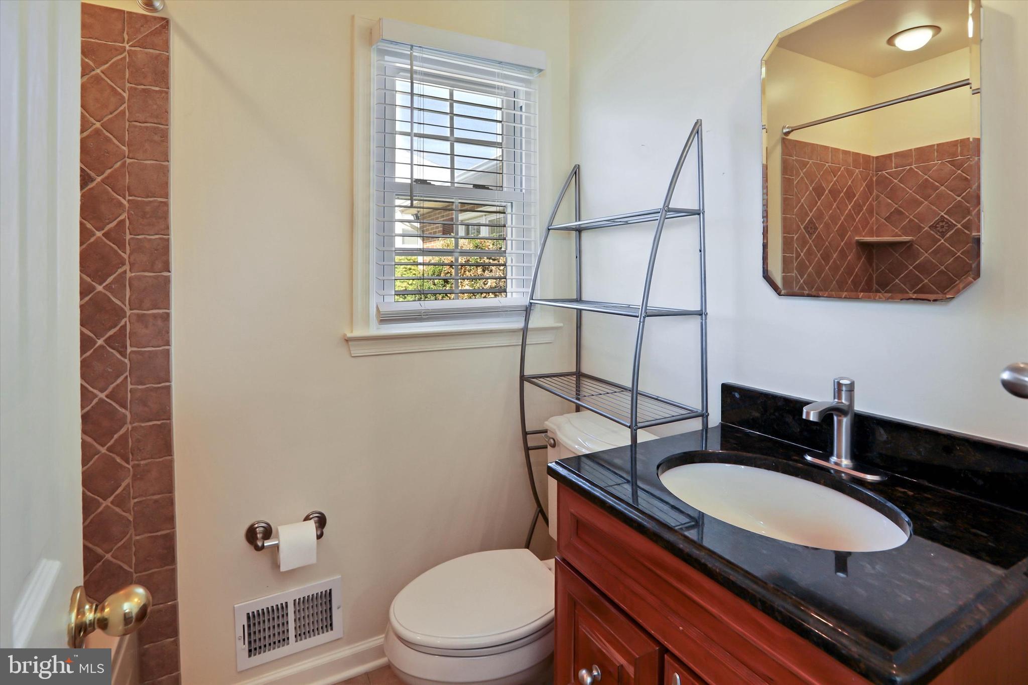 8314 Tinsley Road Baltimore, MD 21244 - Photo 22 of 44 a bathroom with a granite countertop toilet sink and mirror