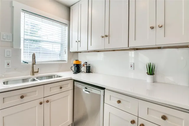 a kitchen with granite countertop white cabinets white appliances and a sink