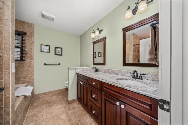 a bathroom with a granite countertop double vanity sink and a mirror