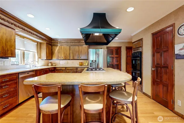 a dining hall with stainless steel appliances a dining table and chairs with wooden floor