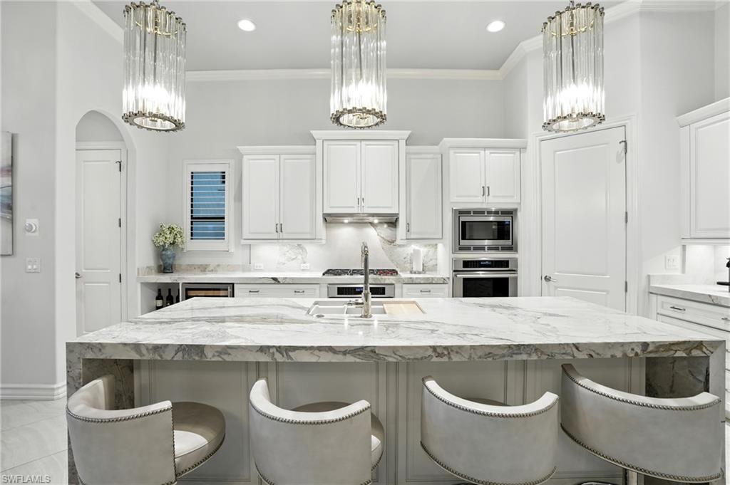 17483 Via Navona Way Miromar Lakes, FL 33913 - Photo 15 of 50 a kitchen with kitchen island granite countertop a sink a stove and cabinets