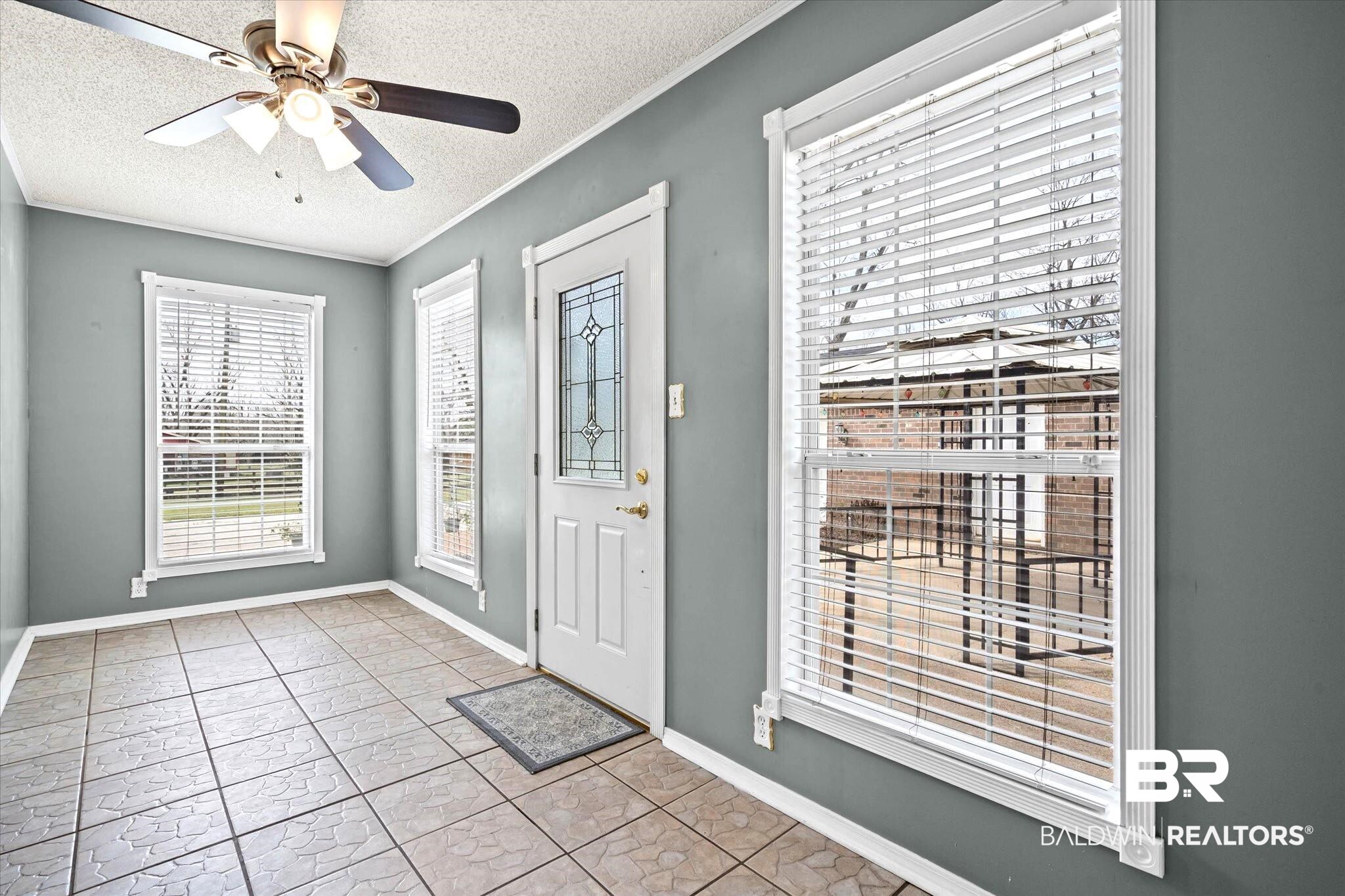 8090 Murray Hill Road Irvington, AL 36544 - Photo 12 of 40 Sunroom featuring a ceiling fan, windows, ornamental molding and door to back yard