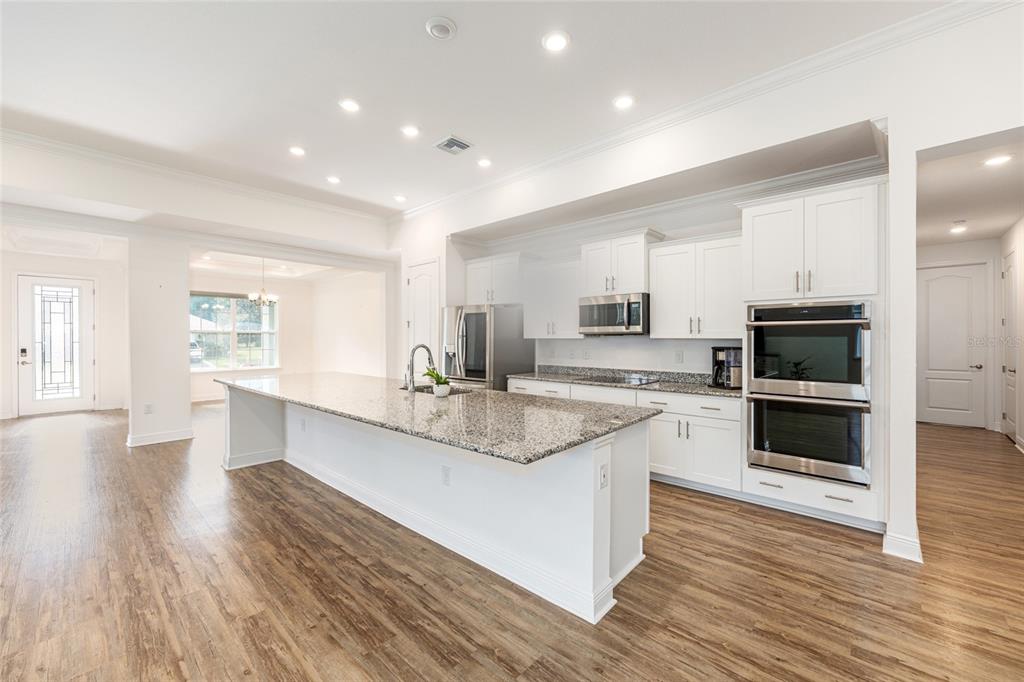 69 Grass Street Homosassa, FL 34446 - Photo 28 of 72 a large white kitchen with stainless steel appliances granite countertop a stove a sink dishwasher and a oven with white cabinets