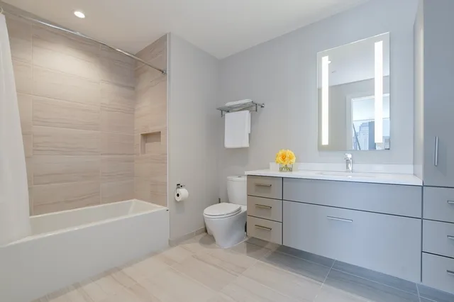 a bathroom with a bathtub shower sink vanity and toilet