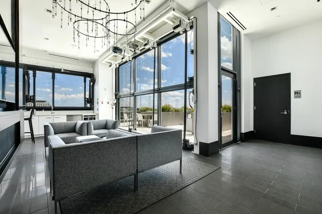 a living room with couches a fireplace and a large window with wooden floor