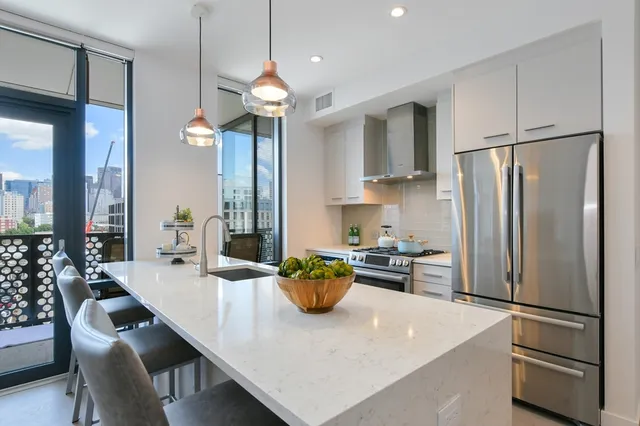 a kitchen with stainless steel appliances a refrigerator a sink a stove and white cabinets