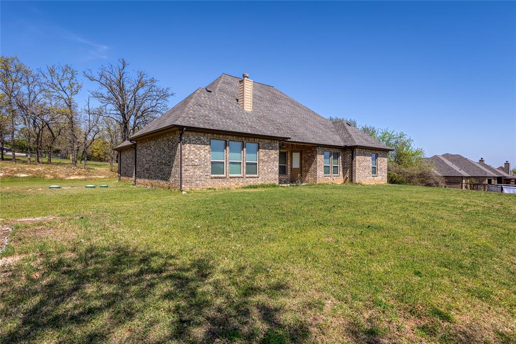 143 Wrigley Drive Springtown, TX 76082 - Photo 34 of 38 Rear view of house featuring a yard, brick siding, and patio area