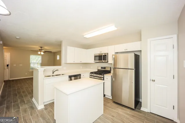 a view of a kitchen with refrigerator and wooden floor