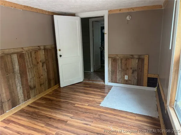 an empty room with wooden floor chandelier and windows