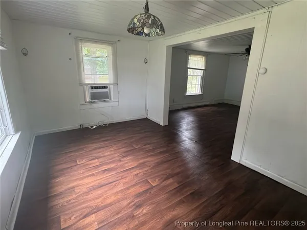an empty room with wooden floor a ceiling fan and windows