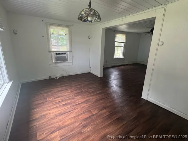 an empty room with wooden floor a ceiling fan and windows